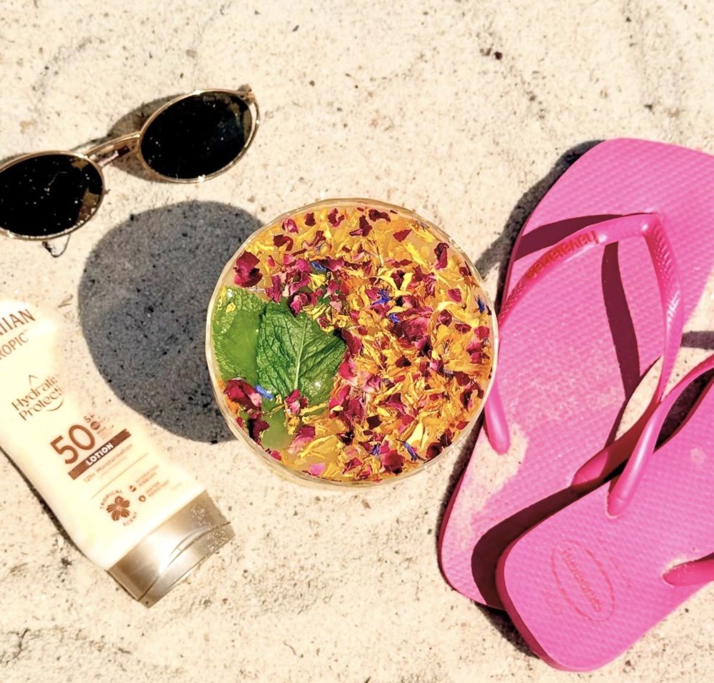 Cocktail aux pétales de fleurs posé sur le sable