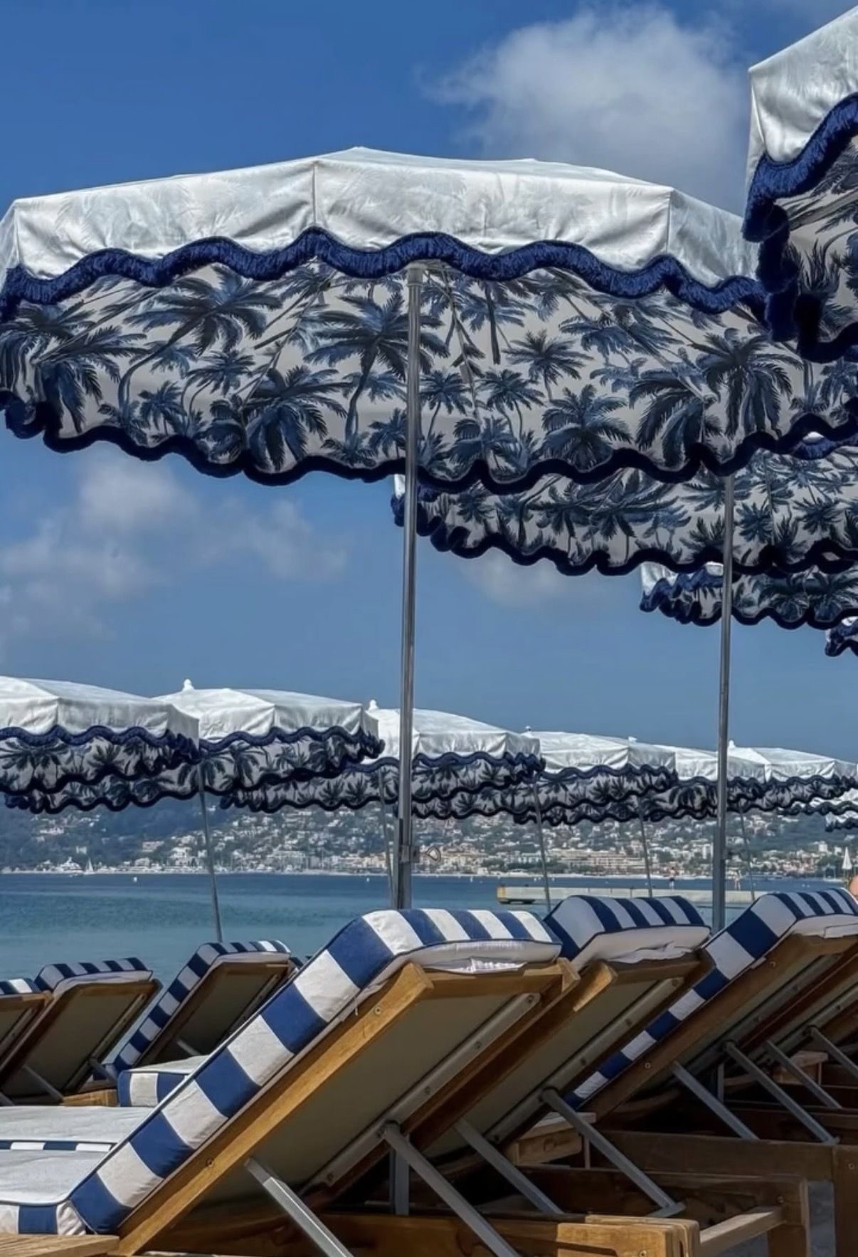 Parasols à franges et transats rayés face à la baie