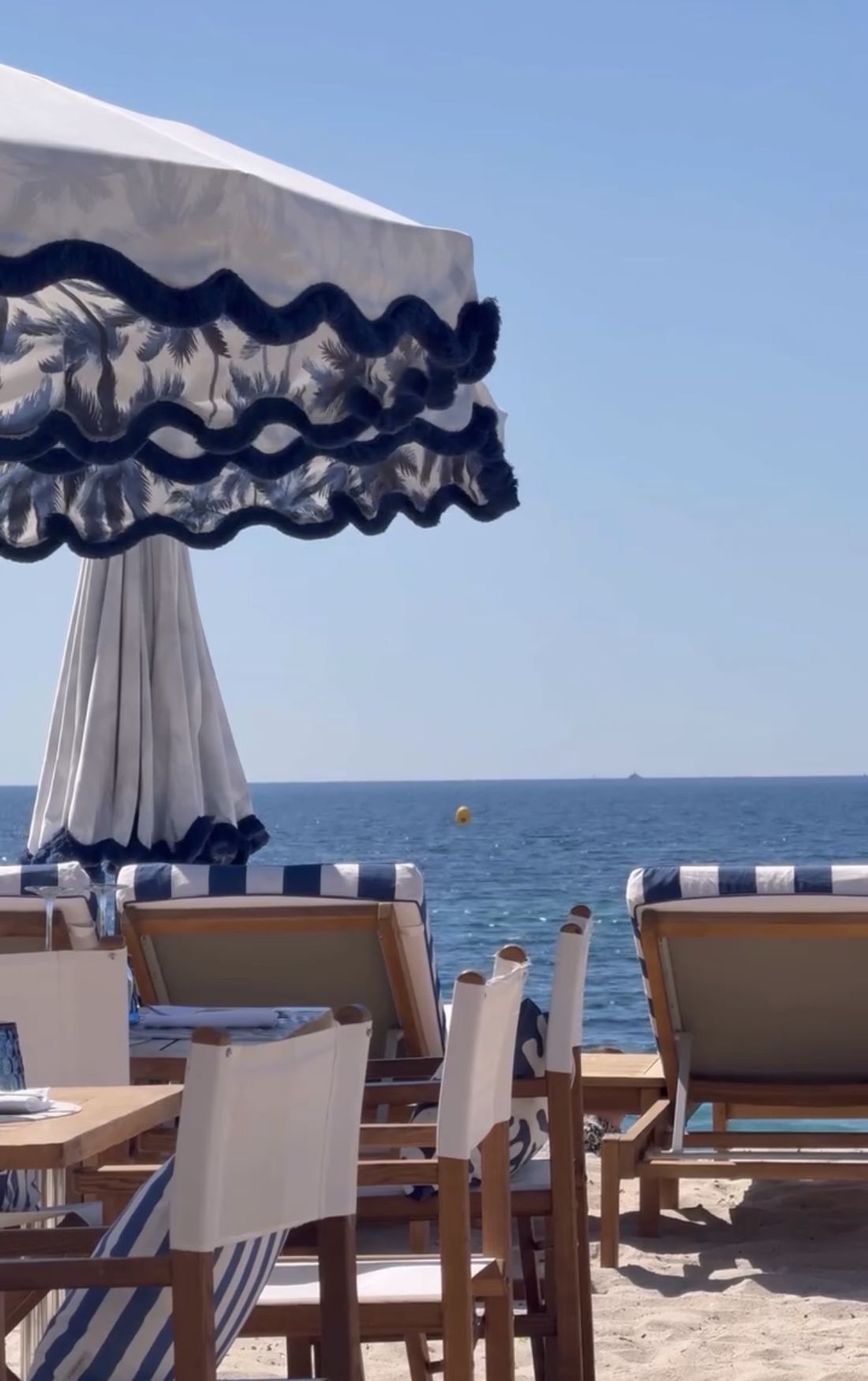 Parasol à franges et chaises de plage face à la mer