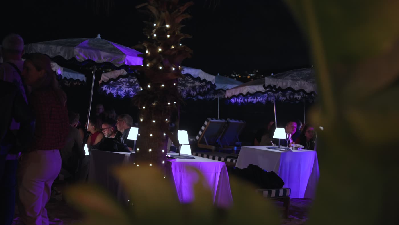 Tables de cocktail illuminées sur la plage le soir
